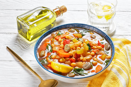 chickpea and green broad bean Moroccan soup in a blue bowl on a white wooden tableの写真素材
