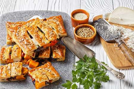 American vegetable puff pastry pie with goat cheese topped with sunflower and sesame seeds filled...