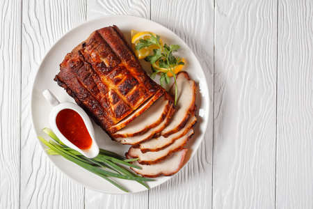 Grilled BBQ Pork Roast cut on slices on a white plate with sauce, horizontal view from above, flat lay, free spaceの写真素材