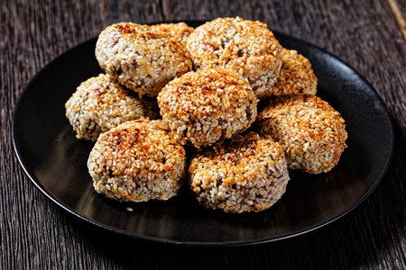 close-up of sesame lamb patties on a black plate on a wooden table