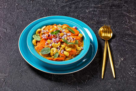 carrot curry with cashew and  raisins in a blue bowl on a concrete table, horizontal view from above, close-up, indian cuisineの写真素材