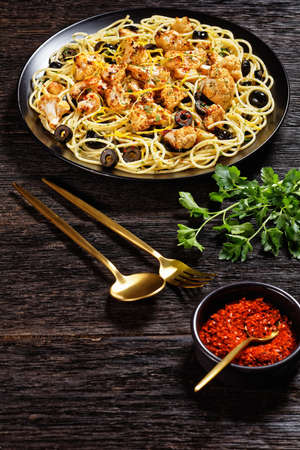 Roasted Cauliflower Pasta with black olives and lemon zest on a black plate on a dark wooden table, flat lay, free spaceの写真素材