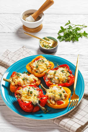 chickpea stuffed peppers are filled with tomatoes, thyme and spices and topped with melted cheddar and goat cheese on a plate, vertical viewの写真素材