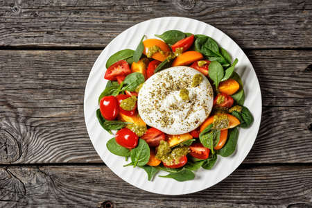 Spinach, Tomato and Burrata cheese Salad with Basil Pesto Dressing on a plate, flat lay, free space, italian cuisineの写真素材