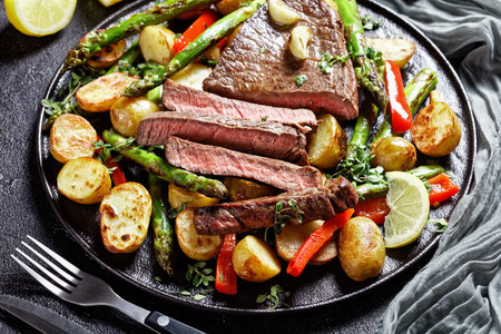 close-up of beef steak with roasted vegetables new baby potatoes, asparagus and red pepper on a...