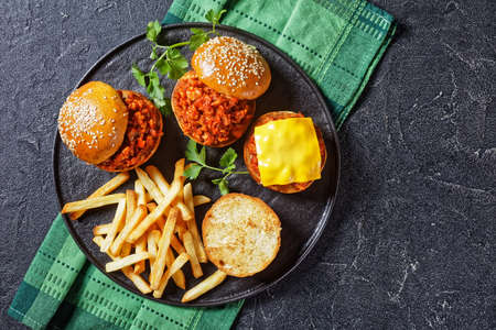 homemade BBQ Sloppy Joe sandwiches with french Fries on a black plate, flat lay, free spaceの写真素材