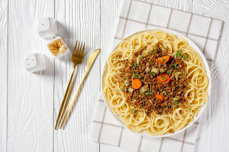spaghetti topped with stewed ground beef ragout with carrots, celery, herbs, horizontal view from above, italian cuisineの写真素材