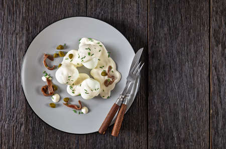 Oeuf mayonnaise, hard boiled eggs covered with a sauce consisting of mayonnaise garnished with snipped chives, capers, and anchovy fillet, french cuisine, flat lay, free spaceの写真素材