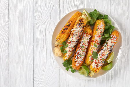 Elotes, Grilled Mexican Street Corn, charred cobs are covered in creamy mayonnaise, seasoned with...