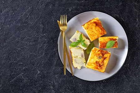 easy chicken breast and egg casserole, chicken meat omelette on a plate with golden fork and knife on a concrete table, flat lay, free spaceの写真素材