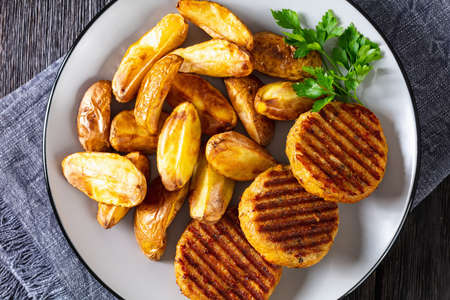 grilled fish burgers with baked potato wedges on a plate, flat layの写真素材