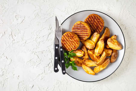 grilled fish burgers with baked potato wedges on a plate, flat lay, free spaceの写真素材