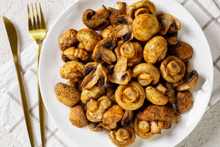 grilled juicy mushrooms on a plate on a white textured table, horizontal view from above, flat lay, close-upの写真素材