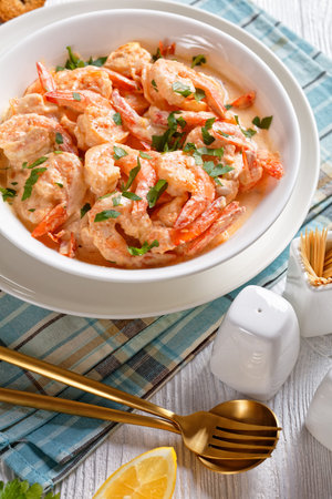 prawns cooked in rich, creamy Alfredo sauce with grated parmesan cheese, garlic and spices served in white bowl with toasted bread, lemon wedges, vertical view, close-upの写真素材