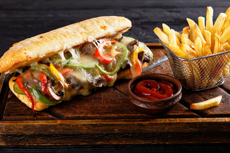 Philly cheese steak sandwich with roasted beef, pepper, caramelized onion, mushrooms and melted cheese with potato friesの写真素材