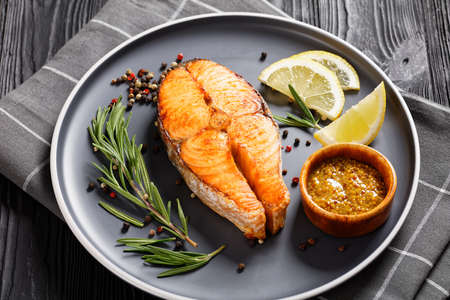 baked salmon steak with wholegrain mustard, lemon, rosemary on a plate, horizontal view from aboveの写真素材