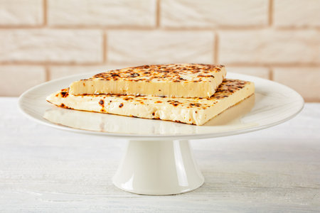 Leipajuusto, kaffeost, bread cheese, finnish squeaky cheese slices on a white cake stand with brick...