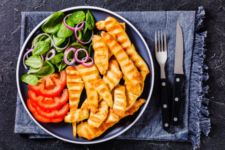 grilled chicken strips on a plate with fresh raw spinach, red onion and tomatoes, keto friendly diet, horizontal view from above, flat layの写真素材