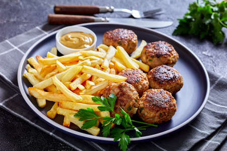 Vitoule, Gehaktballetjes, Belgian meatballs of ground pork and veal on a plate with french fries and mustard sauce on a concrete table, horizontal view from aboveの写真素材