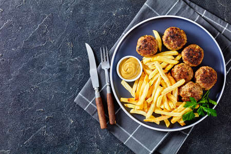 Vitoule, Gehaktballetjes, Belgian meatballs of ground pork and veal on a plate with french fries and mustard sauce on a concrete table, horizontal view from above, flat lay, free spaceの写真素材