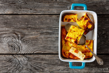 dried apricot Cottage Cheese casserole slices in baking dish on a wooden table, flat lay, free space