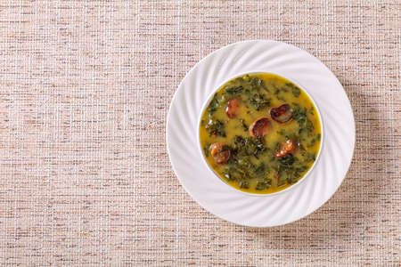 Caldo Verde, Portuguese potato and kale green soup with Chorizo Sausage in bowl on linen cloth, flat lay, free spaceの写真素材