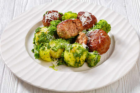Jauhelihapihvit, beef meatballs and boiled new potatoes coated with basil pesto on white plate on wooden tableの写真素材