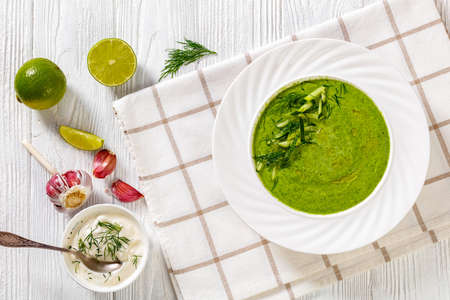 Tarator, summer cold cucumber soup, with dill, yogurt, olive oil in white bowl on white wooden table, mediterranean cuisine, flat lay, free spaceの写真素材