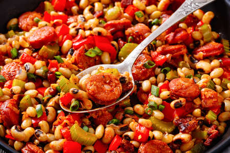 close-up of Hoppin John of black-eyed peas, bacon, sausages, vegetables and scallions with rice in bowl on dark wooden table, traditional Southern american New Year dishの写真素材