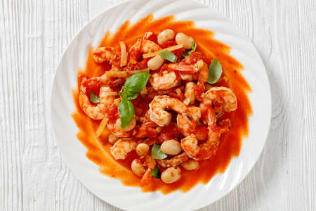 White Bean, Tomato, Fennel and Shrimp Dinner on white plate on white wooden table, horizontal view from above, flat lay, close-up, macroの写真素材
