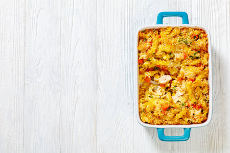 Chicken Pot Pie Fusilli pasta Bake with celery, corn, green peas, carrots , topped with panko breadcrumbs in baking dish on white wood table, copy spaceの写真素材