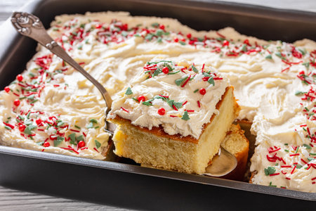 slice of christmas vanilla sheet cake with whipped buttercream frosting garnished with sprinkles on...