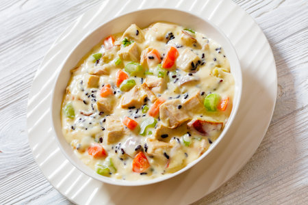 close-up Turkey Wild Rice Soup with red potatoes. carrot, celery, spices and herbs in white bowl on wooden tableの写真素材
