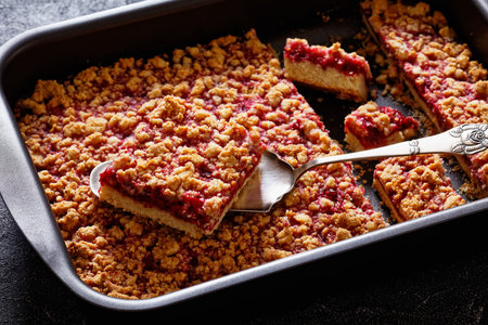 Raspberry Crumble Bars in baking dish on concrete table with cake shovel, close-upの写真素材