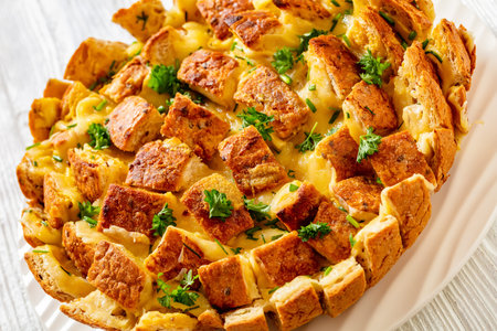 close-up of cheesy garlic bread, pull apart whole round bread on white platter