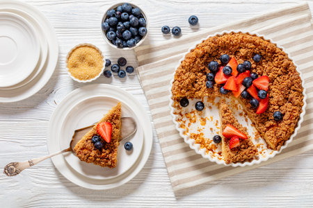 cinnamon baked french toast pie with fresh berries on top on white plate on white wood table, horizontal view from above, flat layの写真素材