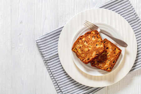 slices of apple cinnamon bread on white plate with dessert knife on white wood table, horizontal view from above, flat lay, copy spaceの写真素材