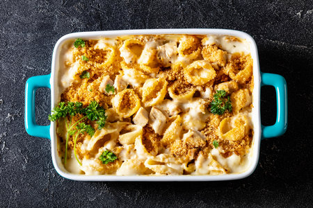cheesy and creamy chicken and shells pasta bake in baking dish on dark gray concrete table, horizontal view from above, flat lay, close-upの写真素材