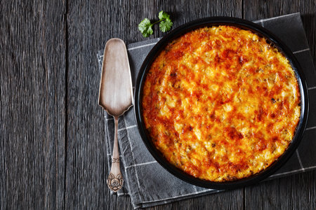 Cheesy Loaded Grits bake with ground meat on baking dish on dark wood table, horizontal view from above, flat lay, free spaceの写真素材