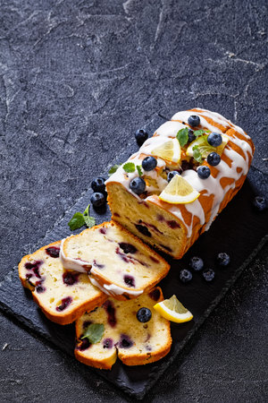 Lemon Blueberry Pound cake with Lemon Glaze on slate board on dark concrete table with fresh blueberries, vertical view from aboveの写真素材