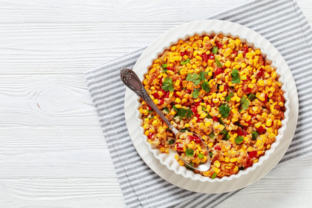 New Orleans Style Corn casserole with sweet red pepper,american recipe,butter, crackers and eggs in white dish with spoon, flat lay, free spaceの写真素材