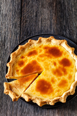 classic sugar cream pie, hoosier pie, indiana custard cream pie on black plate on dark wood table, american cuisine,, vertical view from above, free spaceの写真素材