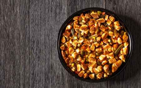 retro okra and rice casserole loaded with tomatoes, corn, onion and spices, topped with croutons in baking dish on dark wood table, horizontal view from above, american cuisine, flat lay, copy spaceの写真素材
