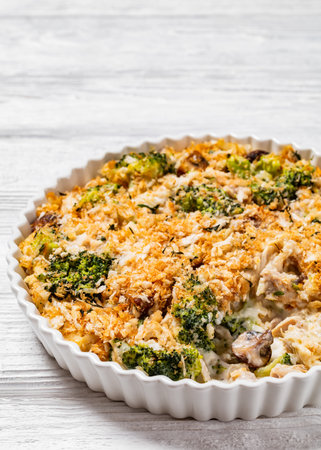 Chicken, Broccoli and mushrooms creamy Casserole topped with panko breadcrumbs in baking dish on white wooden table, vertical view, free spaceの写真素材