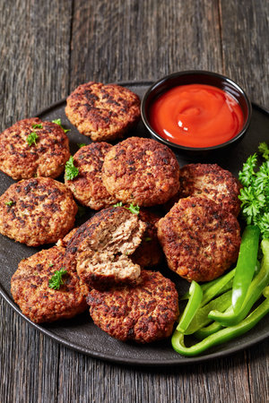german frikadellen of ground beef and pork, breadcrumbs, onions and spices on black plate with...
