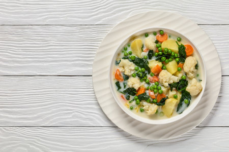 Kesakeitto, Finnish summer vegetable soup with milk and butter in white bowl on white wooden table, horizontal view from above, flat lay, free spaceの写真素材