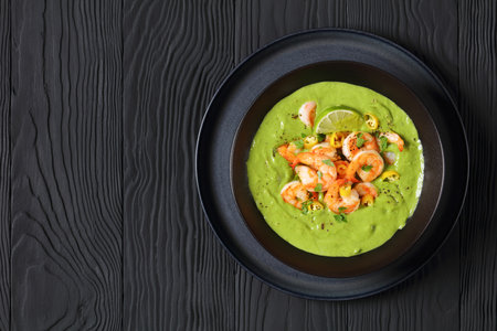 Shrimps in Culichi Salsa or Poblano sauce in black bowl on black wooden table, horizontal view from above, flat lay, free spaceの写真素材