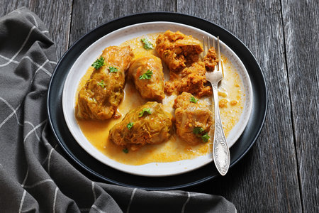cabbage rolls with quinoa and ground chicken filling on a plate with fork on dark wood table ,horizontal view from above, close-up, real photo, not AI generatedの写真素材