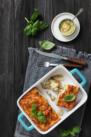 Freshly baked cheesy egg sausage casserole in a ceramic blue dish with basil and Dijon mustard, vertical top view, no AIの写真素材