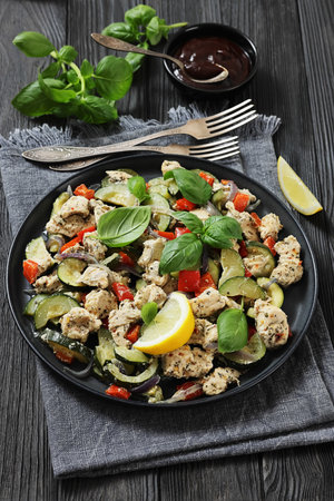 baked italian chicken and vegetables, juicy chunks of chicken with zucchini, bell peppers and italian seasoning sprinkled with fresh basil on a plate, vertical view, not AI generatedの写真素材